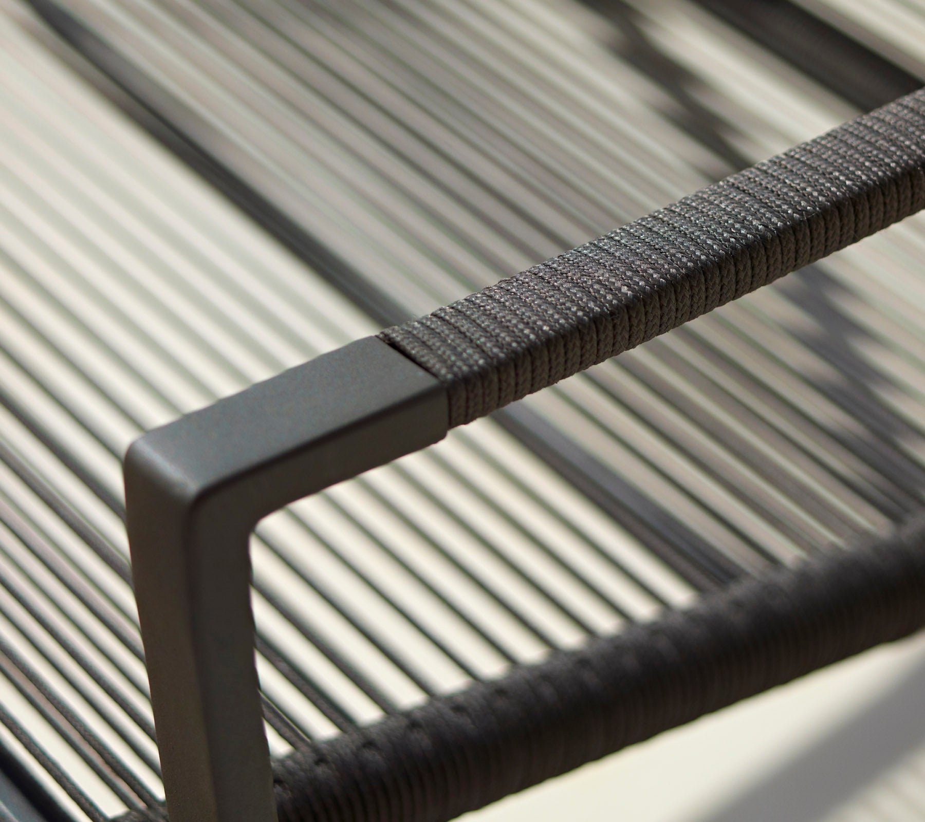 Close-up of a modern chair's armrest featuring a sleek design with textured detailing and a minimalistic black finish.