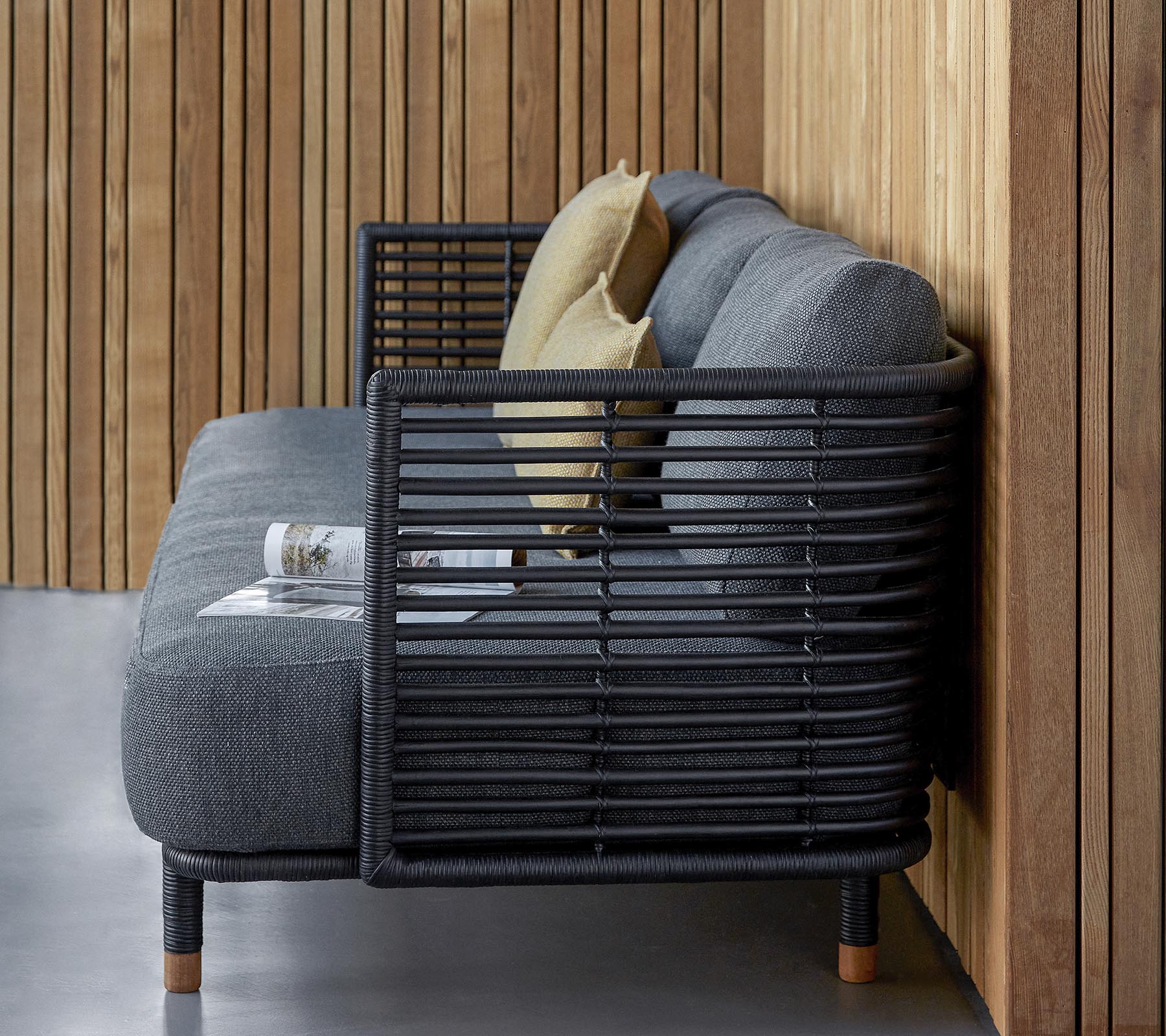 Stylish sofa featuring a sleek design with a textured gray fabric and decorative cushions, complemented by a modern slatted frame.