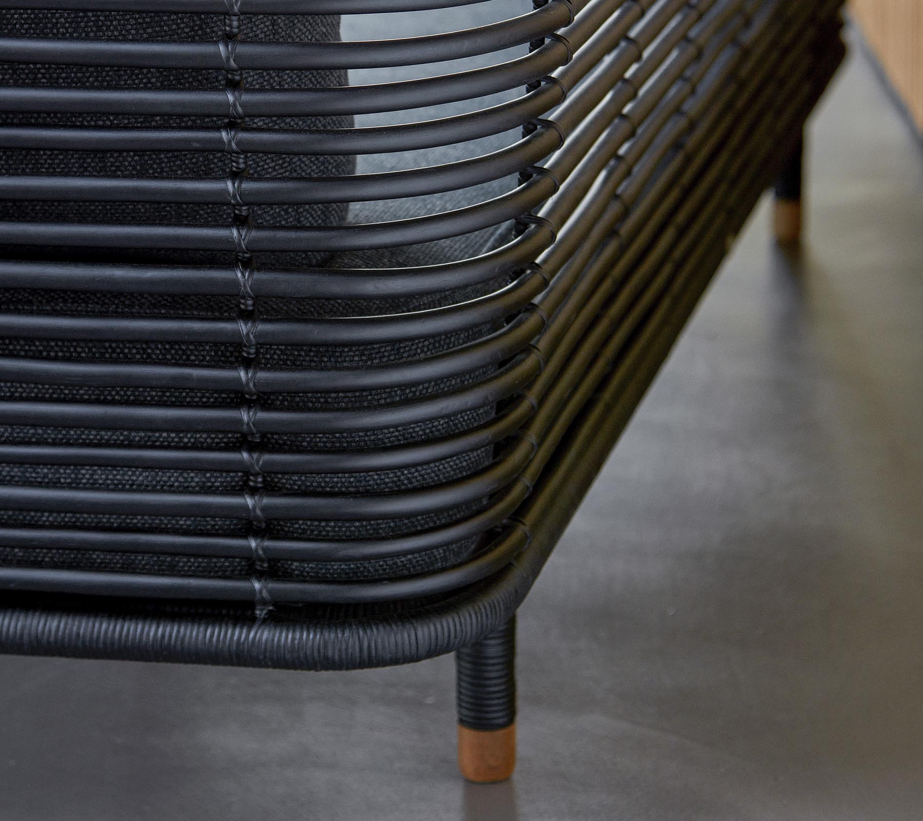 Stylish black woven furniture with curved lines and wooden accents, showcasing a modern design aesthetic. A perfect addition to any space.