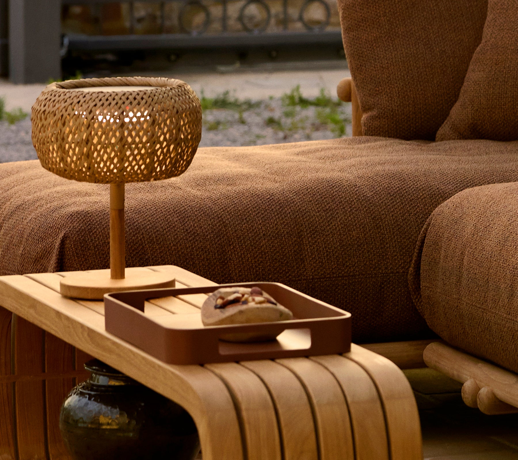 A wooden coffee table showcasing a decorative tray and a woven lamp, enhancing a cozy and stylish atmosphere.