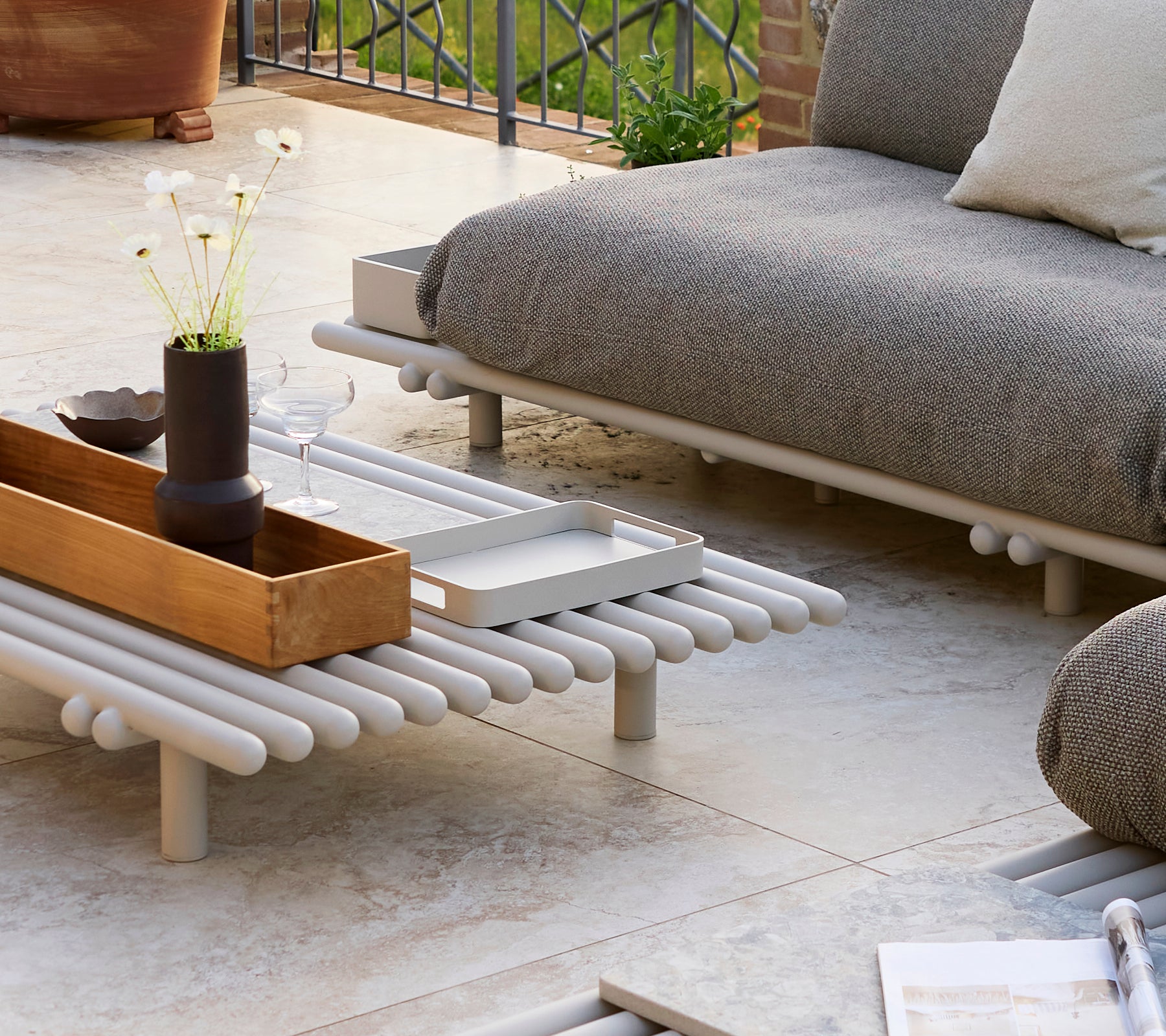 A small rectangular tray on a platform coffee table with decorative items and a minimalist design.