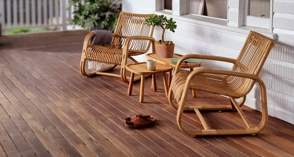 Two Curve lounge chairs in natural colour on the veranda with teak side tables