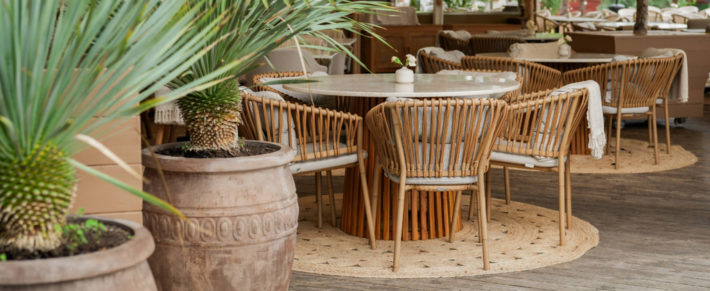 Restaurant Josefina interior with round table, palms and Cane-line Ocean chairs in natural Cane-line Weave