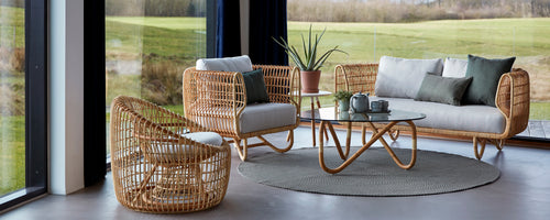 Cozy lounge seating with rattan furniture, soft cushions, a glass table, and decorative plants, creating a stylish and inviting atmosphere.