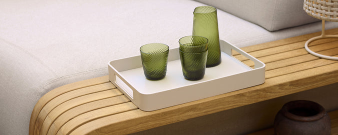 A stylish serving tray with green glasses arranged on a wooden surface, complementing a minimalist aesthetic.