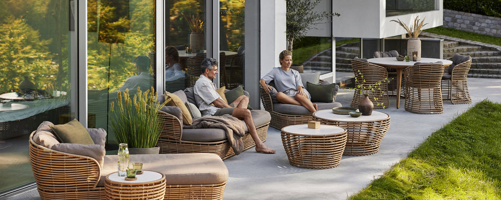 Modern rattan chairs with grey cushions and a coffee table in a contemporary outdoor lounge setting.