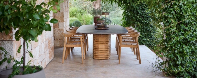 Outdoor wooden dining chairs surrounding a black table in a green garden setting.
