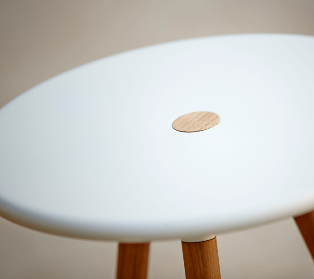 A stylish stool with a smooth white top featuring a small wooden accent, supported by wooden legs. Ideal for modern decor.