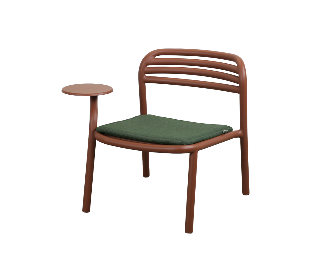 Modern chair in desert red with a green cushion and a side table.