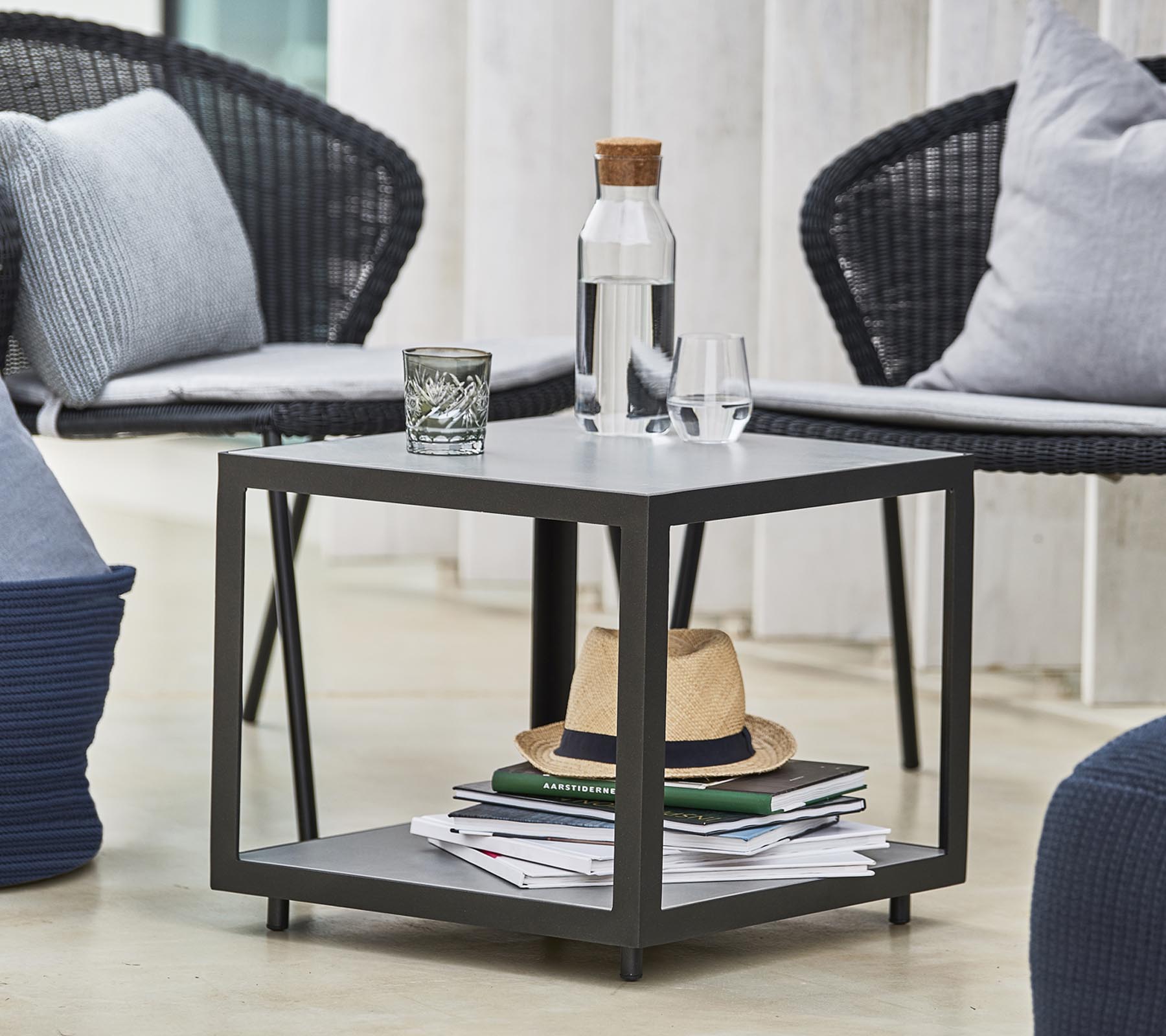 A modern table with a water bottle, glass, and decorative items, surrounded by stylish chairs and cushions.