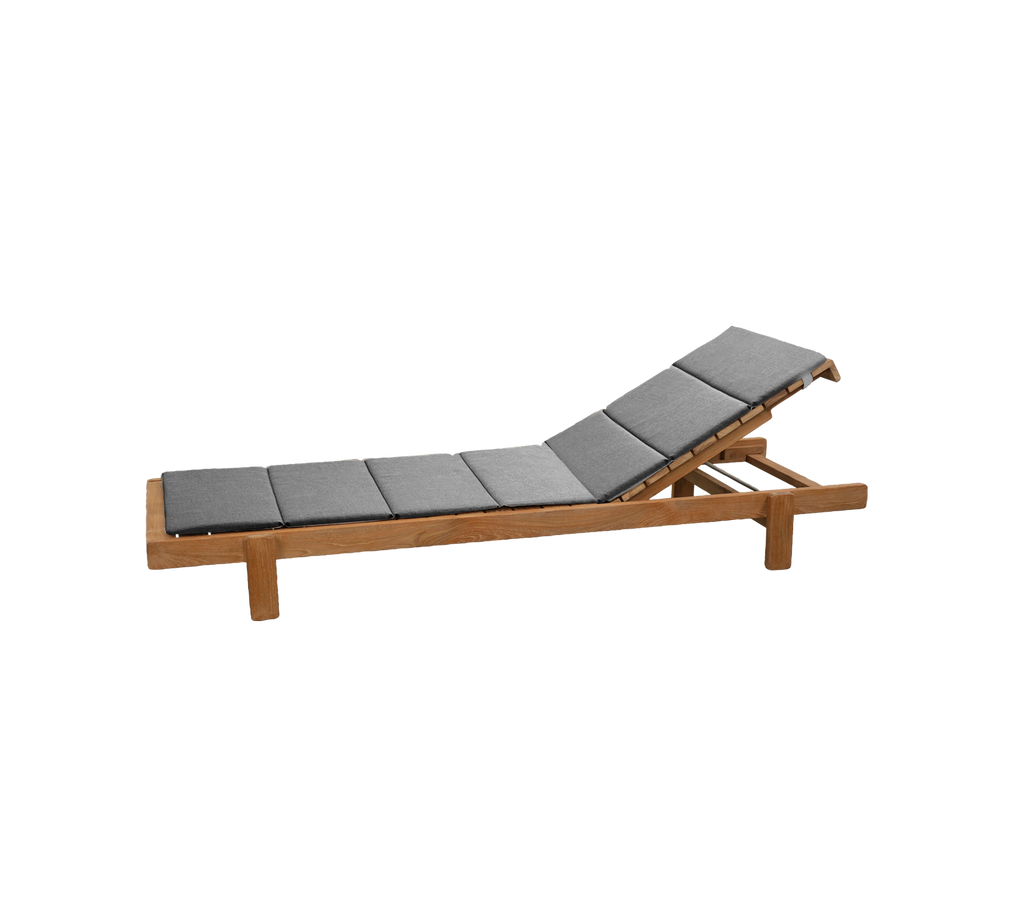 Teak lounger with grey cushion in a lounge setting.