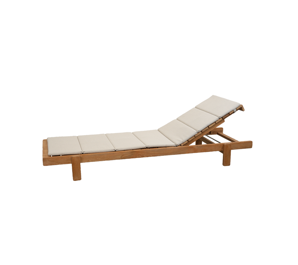Teak lounge chair with sand cushion in a modern outdoor setting.