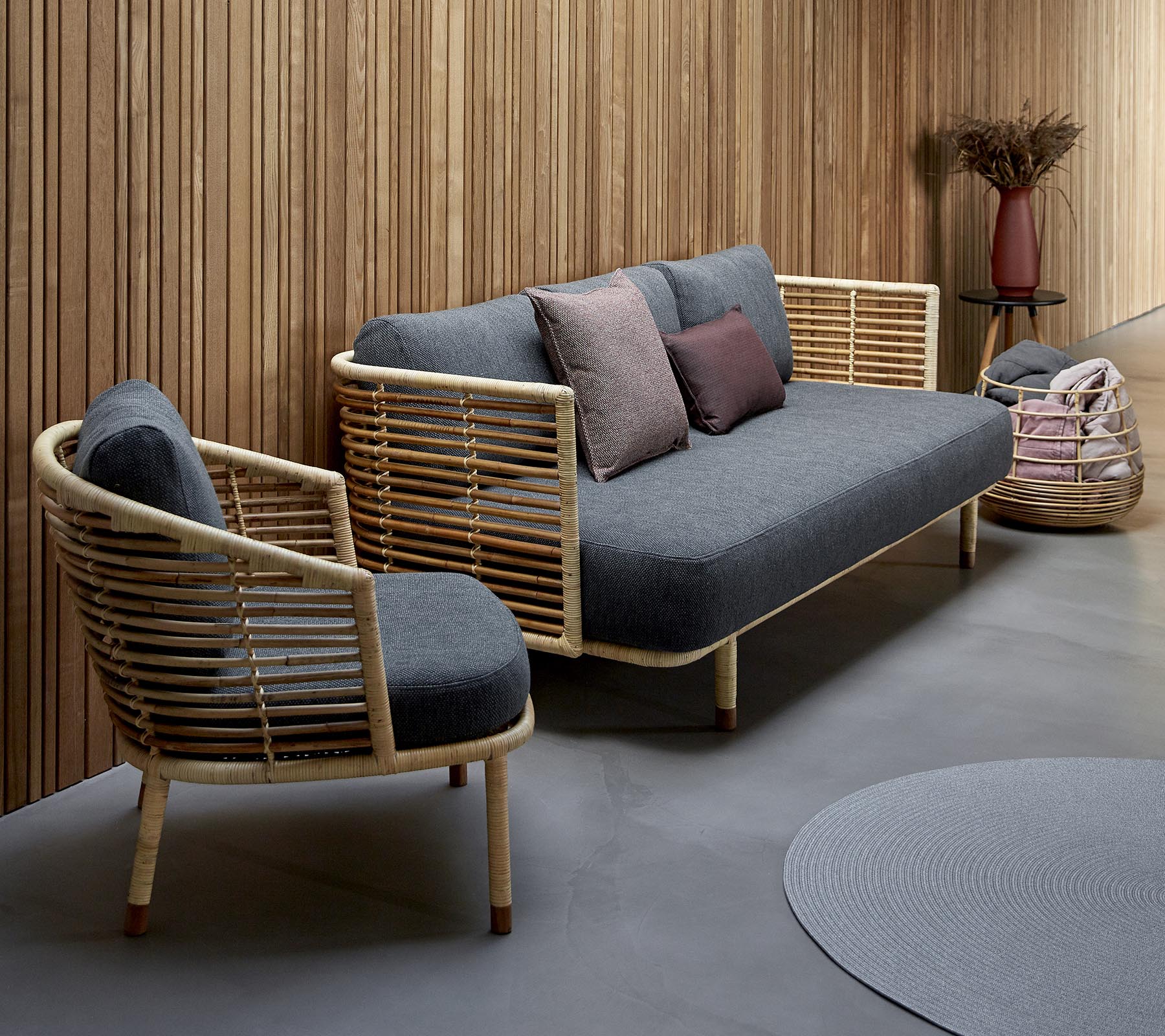 Stylish seating arrangement featuring a gray upholstered sofa with wooden accents and matching chair, complemented by decorative pillows.