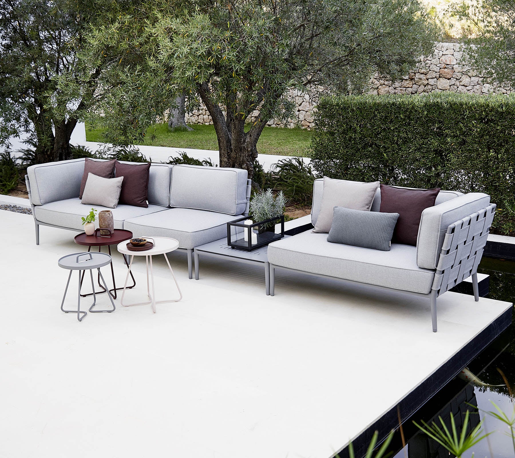 Modern outdoor seating arrangement with cushions, accompanied by a stylish side table and decorative plants.