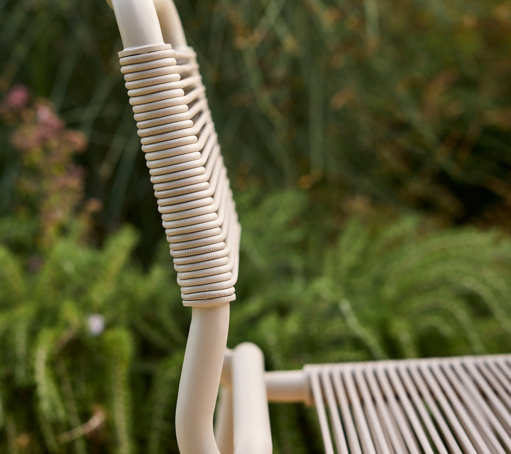 Beige chair partially shown with a blurred green background.
