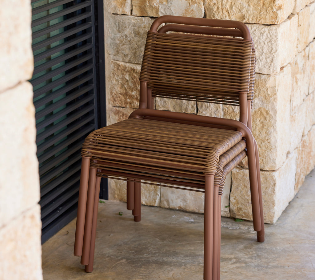 Brown chair with a modern design against a stone wall.