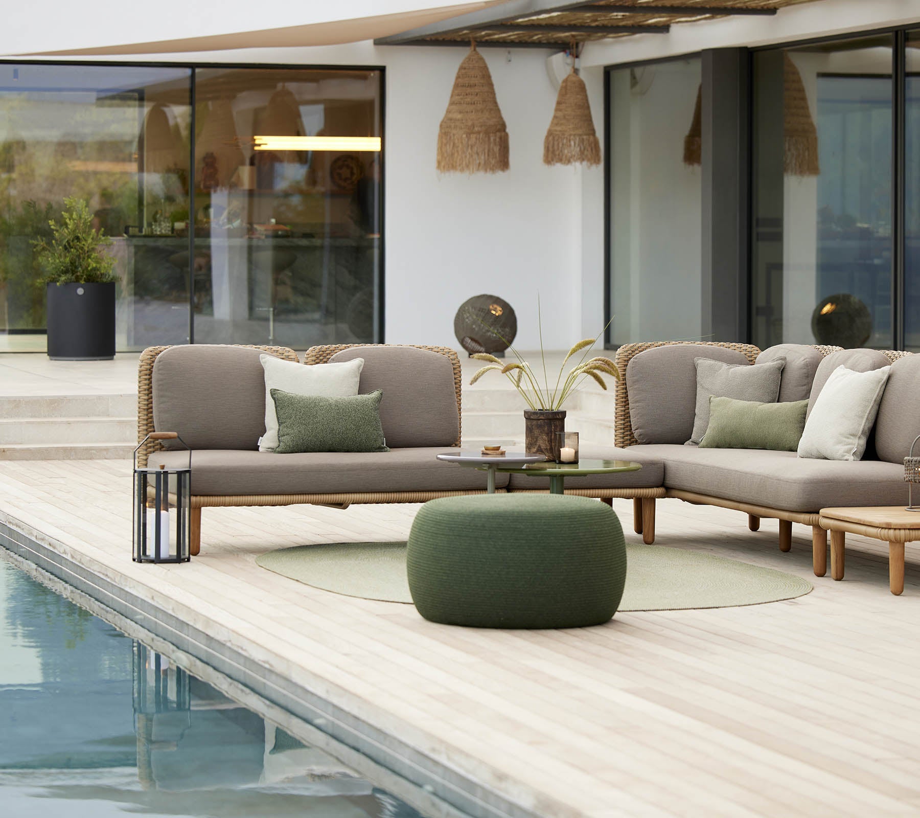 Stylish seating area featuring a cozy circle footstool and an arch-shaped design, complemented by decorative cushions and greenery.