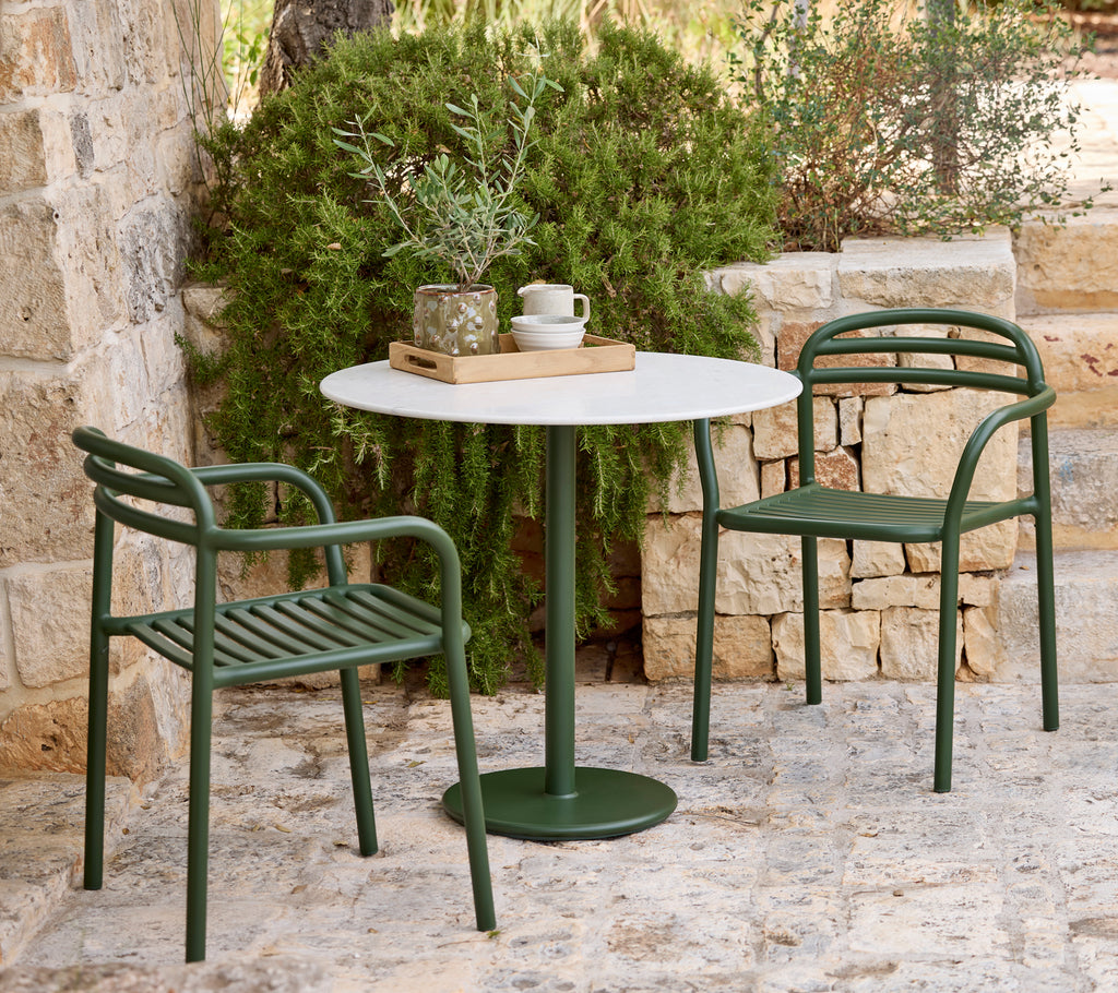 Modern outdoor setting with green chairs and a white table.