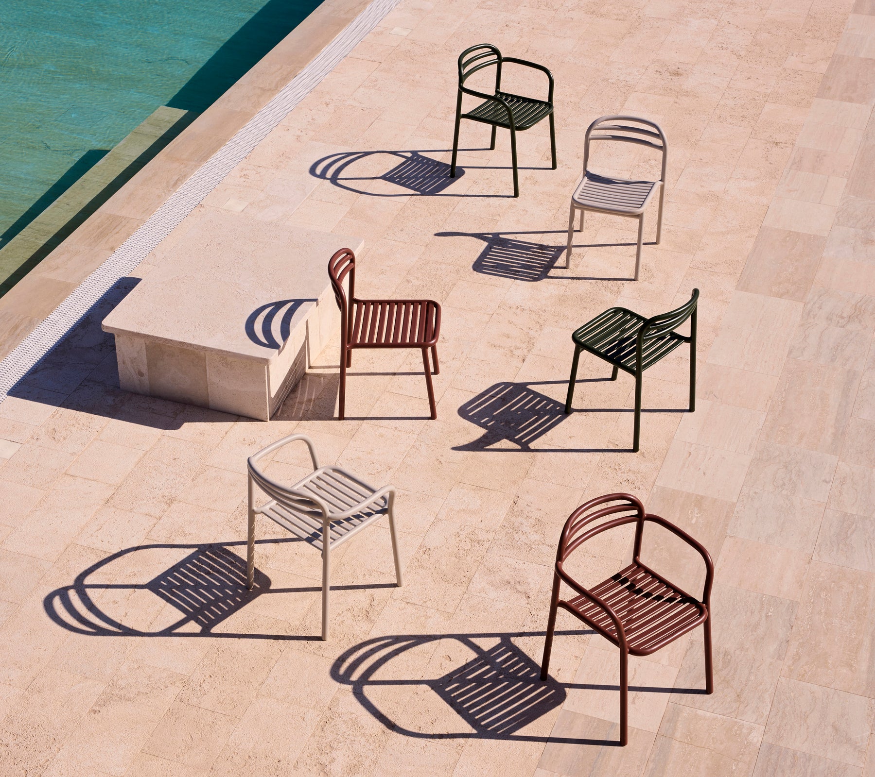 A collection of Bliss chairs with armrests in various colors, casting shadows on a light surface.