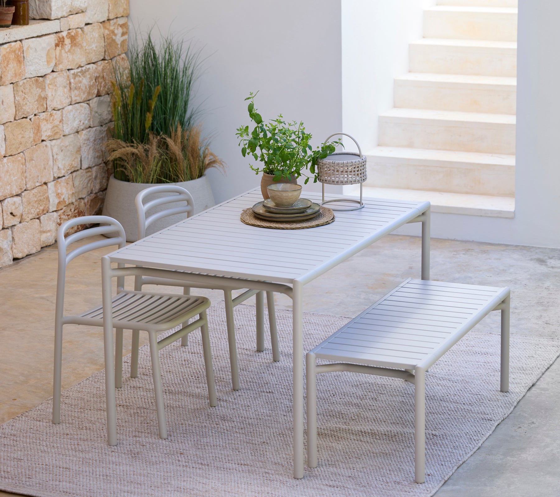 Light grey dining set including a table, chairs, and bench in a modern outdoor setting.