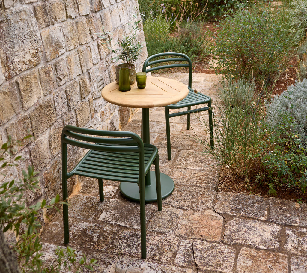 Outdoor setting with a green chair, wooden table, and glass vase.