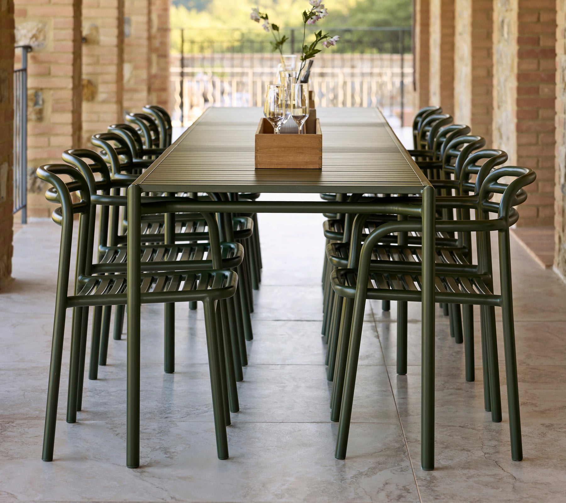 A long table set with dark green Bliss chairs featuring armrests, complemented by a decorative centerpiece.