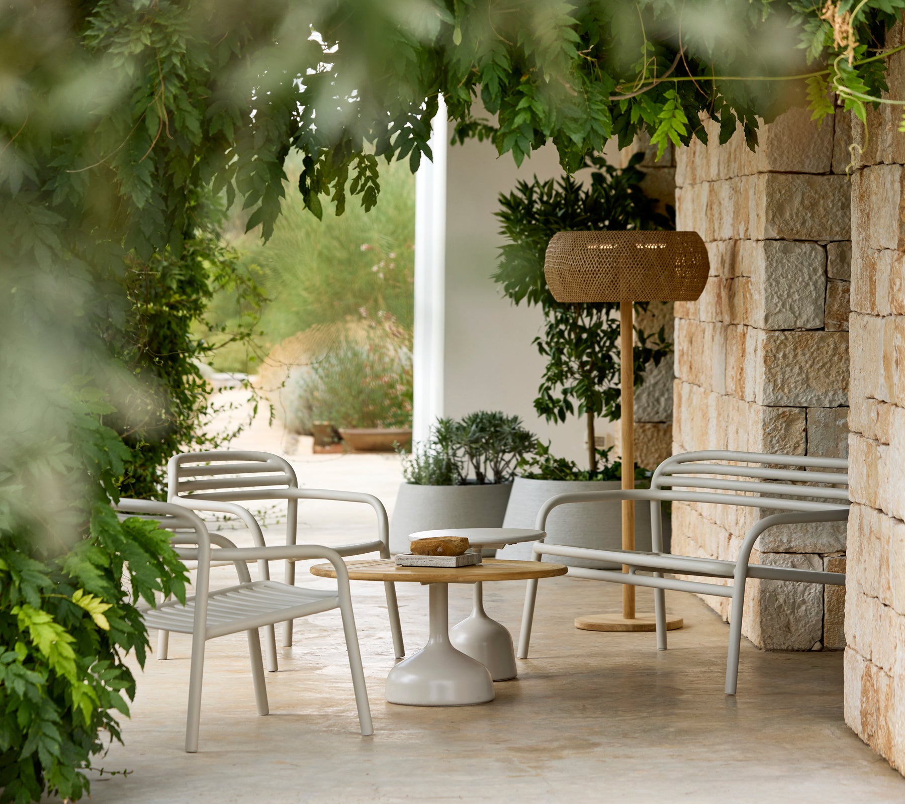 Modern lounge area featuring white chairs and a round table surrounded by greenery.