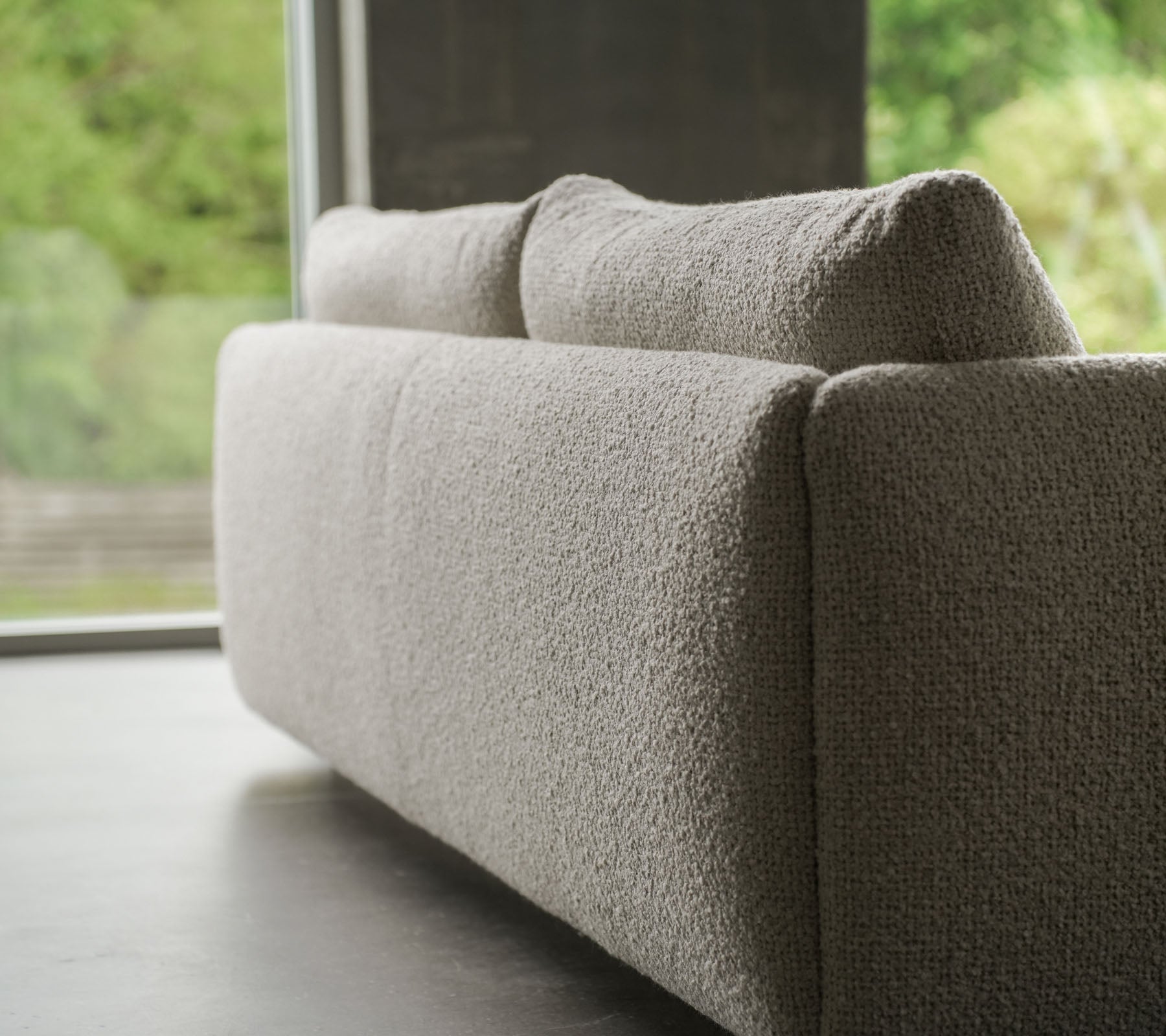 Contemporary sofa with a textured sand-colored fabric, accented by elegant teak legs, showcasing Cane-line flair and plush cushions.
