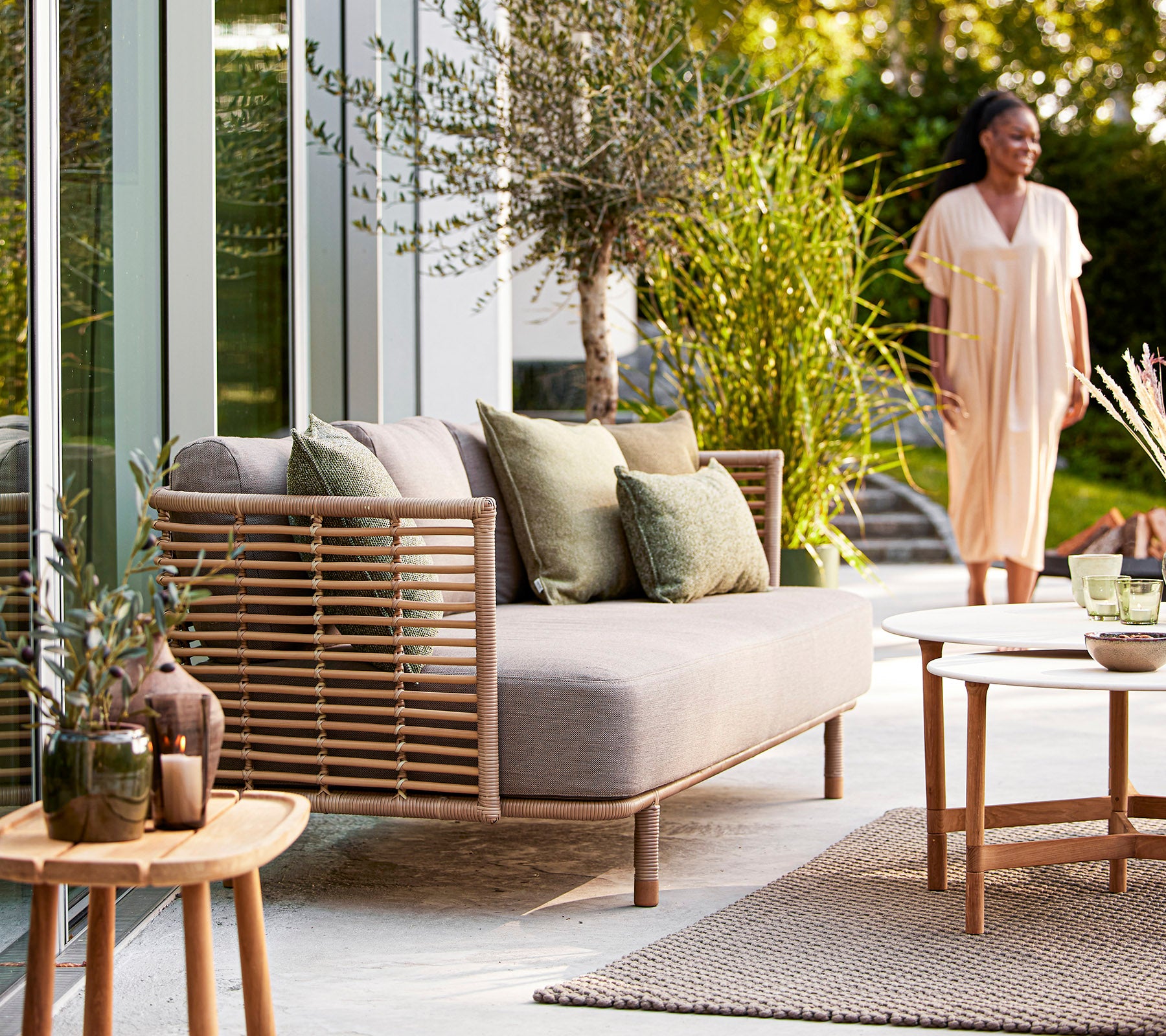 A cozy seating area with a light sofa, green cushions, decorative plants, and a wooden table, creating an inviting atmosphere.