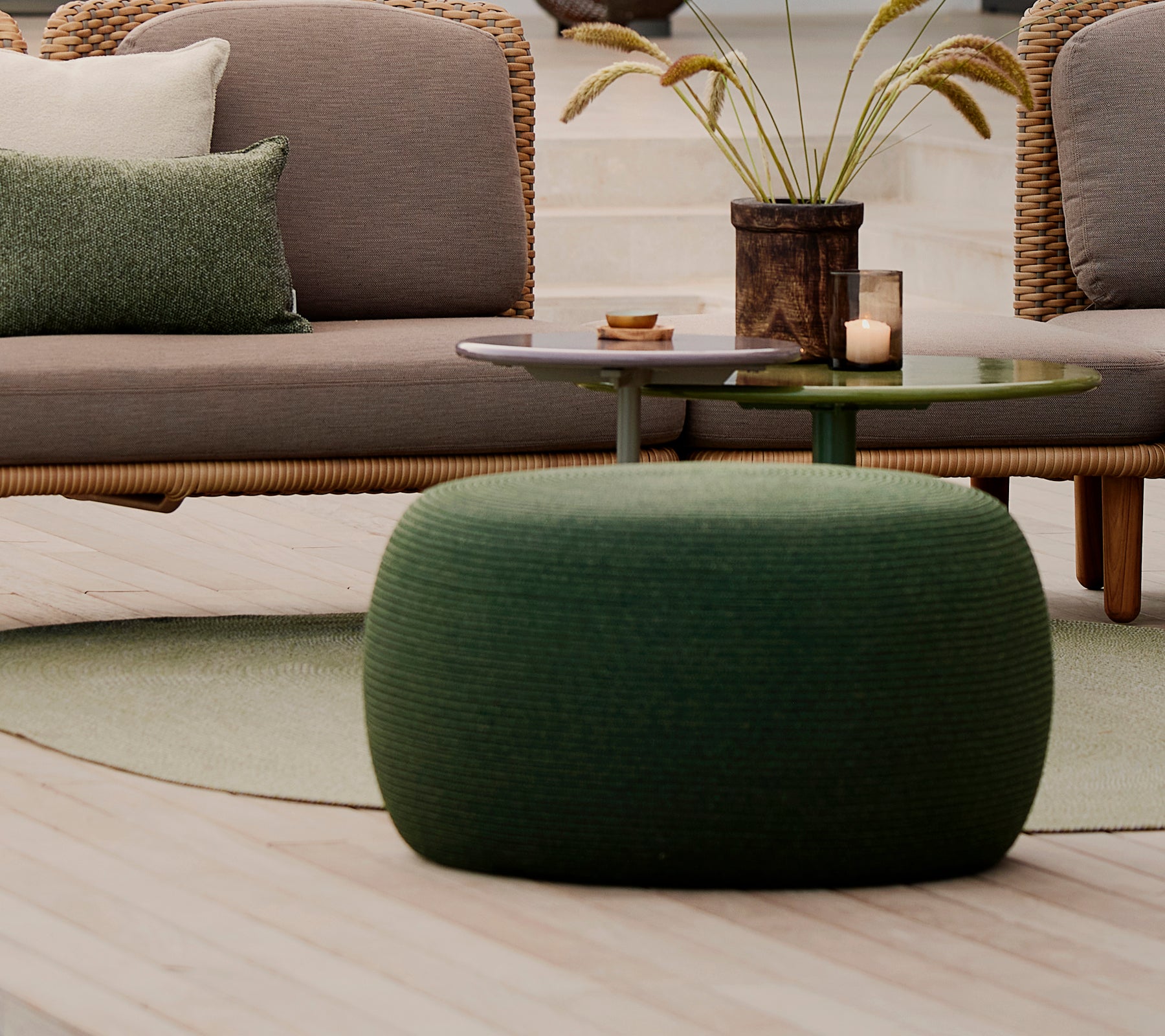 Large green circle footstool with a textured surface, accompanied by a small table and decorative elements.