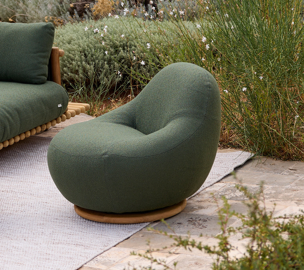 A dark green chair with a rounded design in a modern lounge setting.
