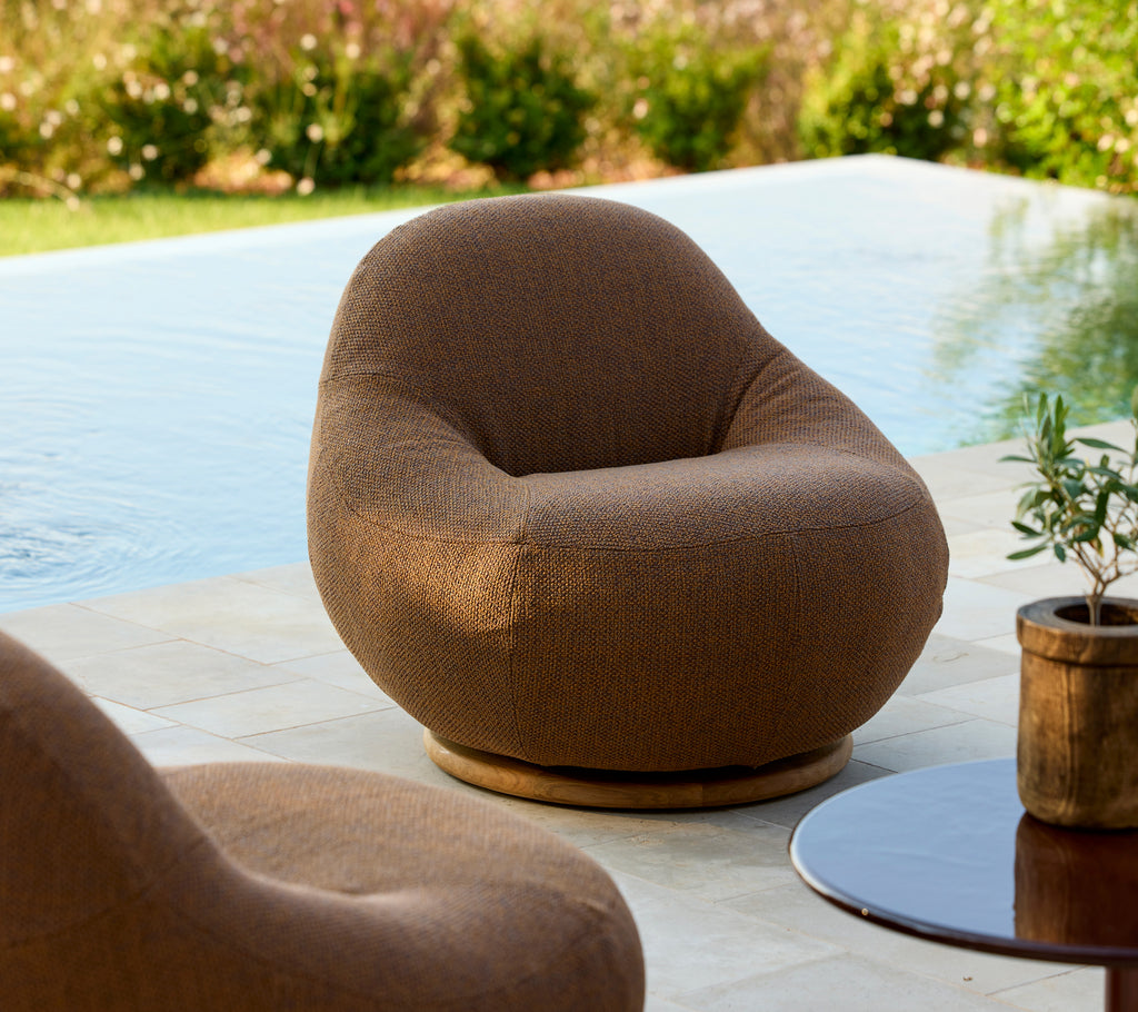 Round brown chair and wooden table in a modern outdoor lounge setting.