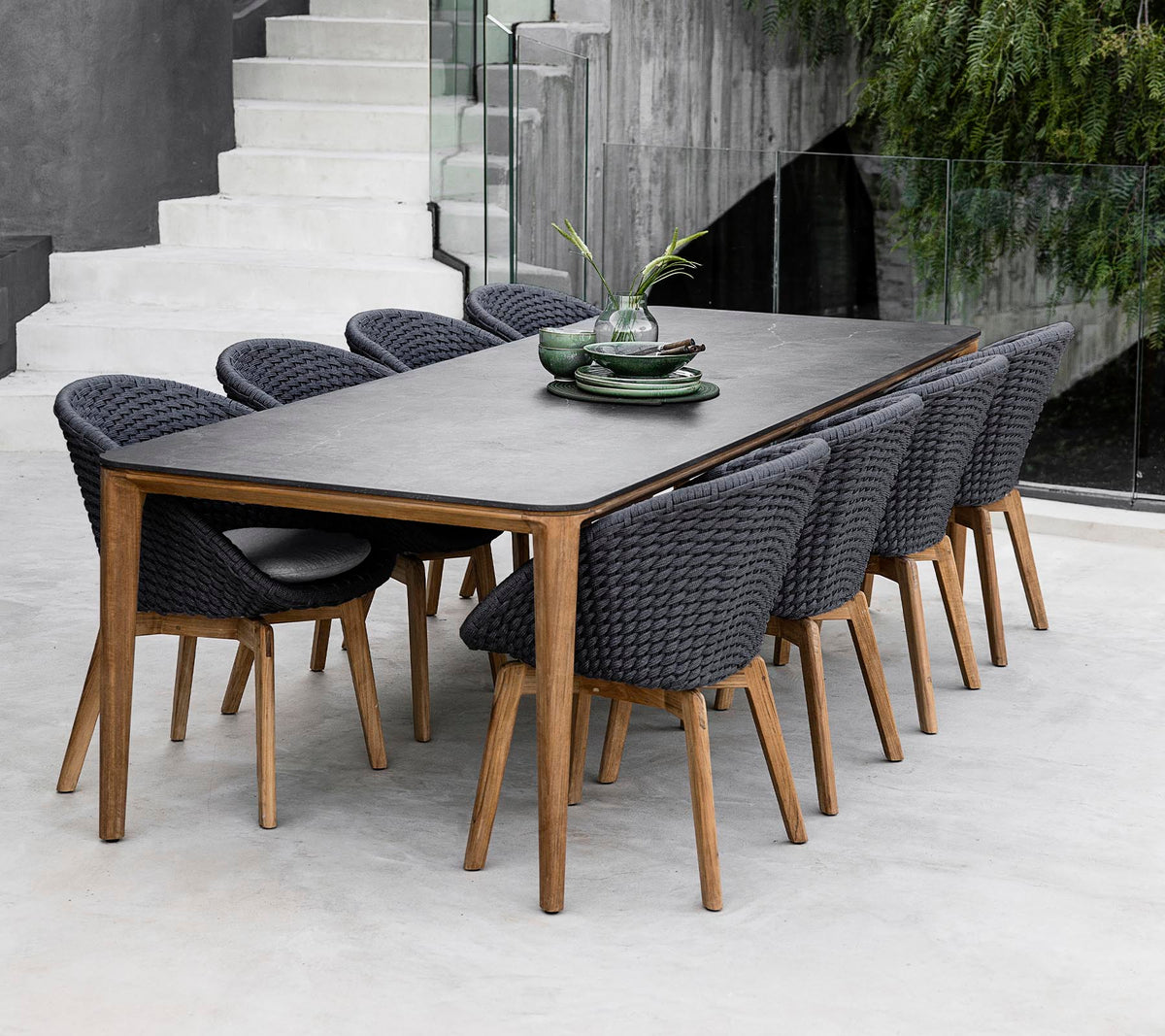 A modern table surrounded by eight stylish chairs, adorned with decorative plants on the table in a sleek, minimalist setting.