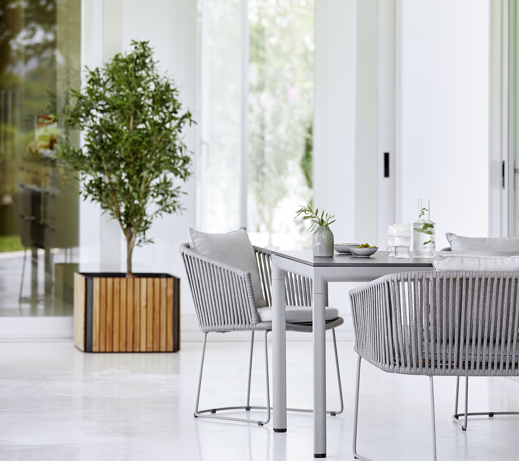 A modern dining area featuring a sleek table, textured chairs, and a decorative potted plant, creating a stylish and inviting atmosphere.