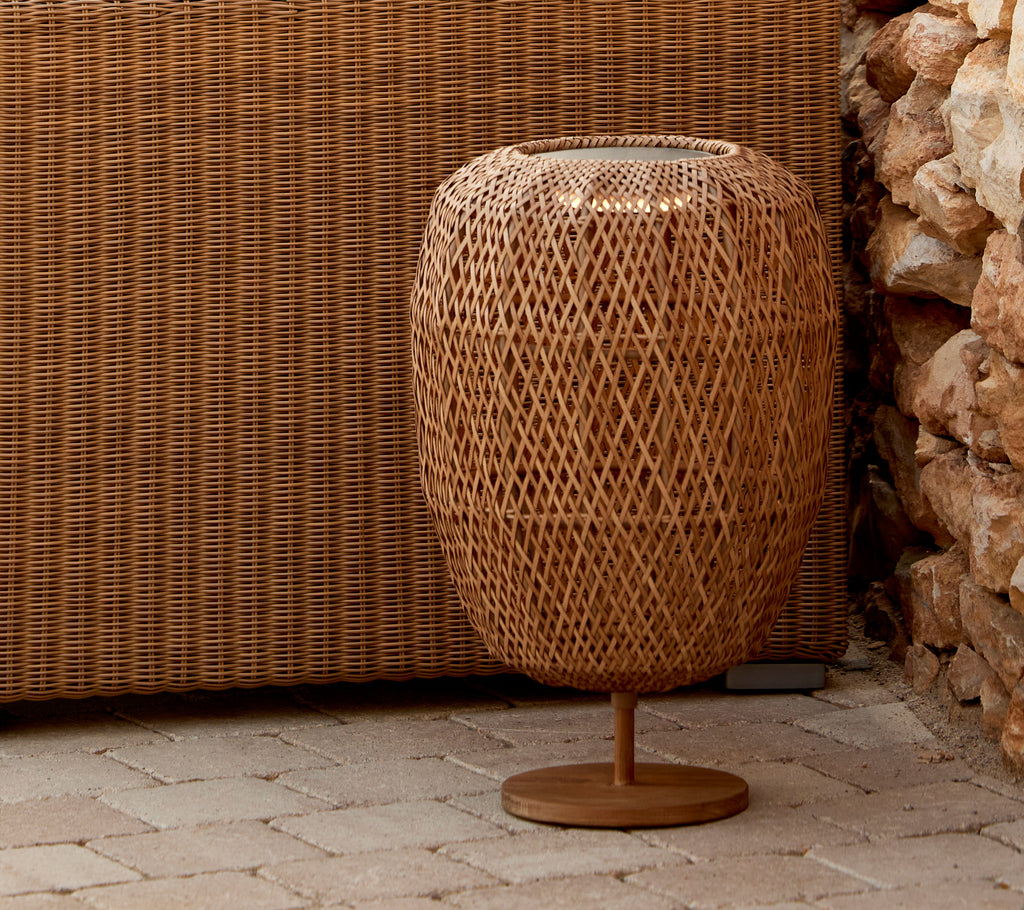A medium table lamp with a woven design, featuring a round base and an intriguing light glow effect. Perfect for enhancing ambiance.