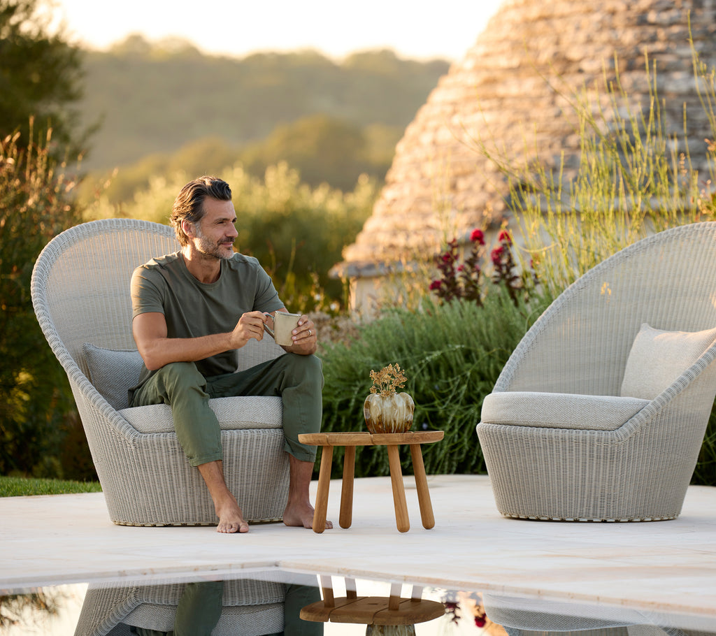 Modern grey lounge chairs with a wooden table beside a pool.