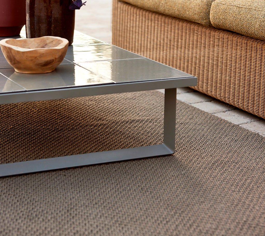 Knit rug paired with a glaze coffee table and a wooden bowl on top, creating a stylish and cozy setting.