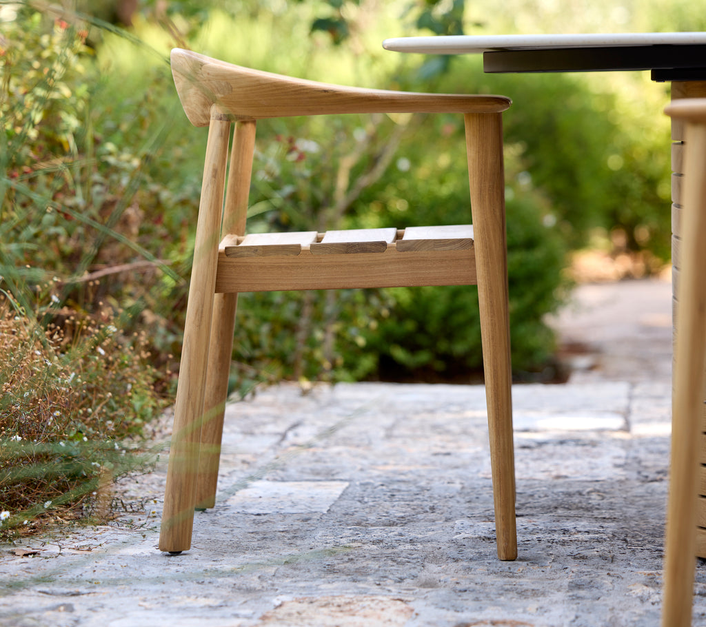 Modern wooden chair beside a black table in an outdoor setting.