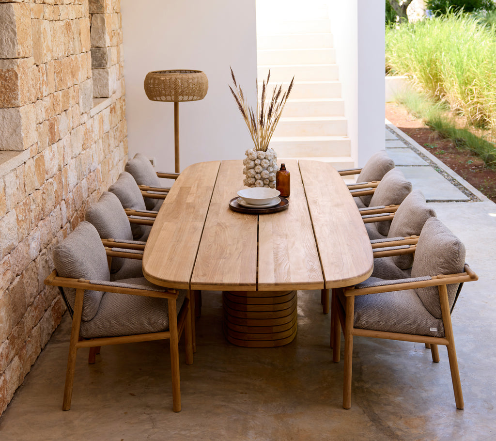 Modern dining setup with wooden table, grey cushions, and wooden chairs.