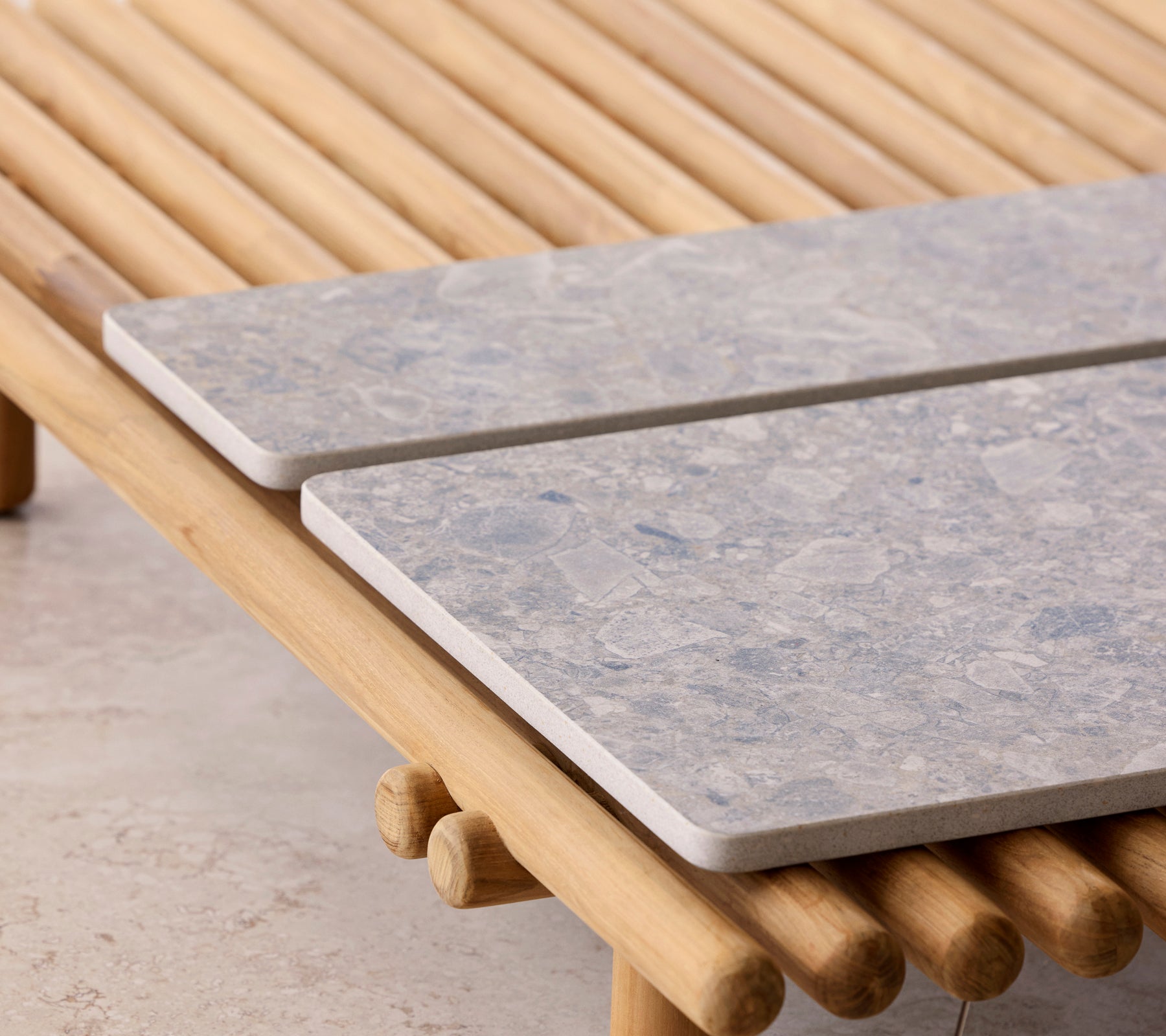 A coffee table featuring a stick design with two stone tabletops resting atop.