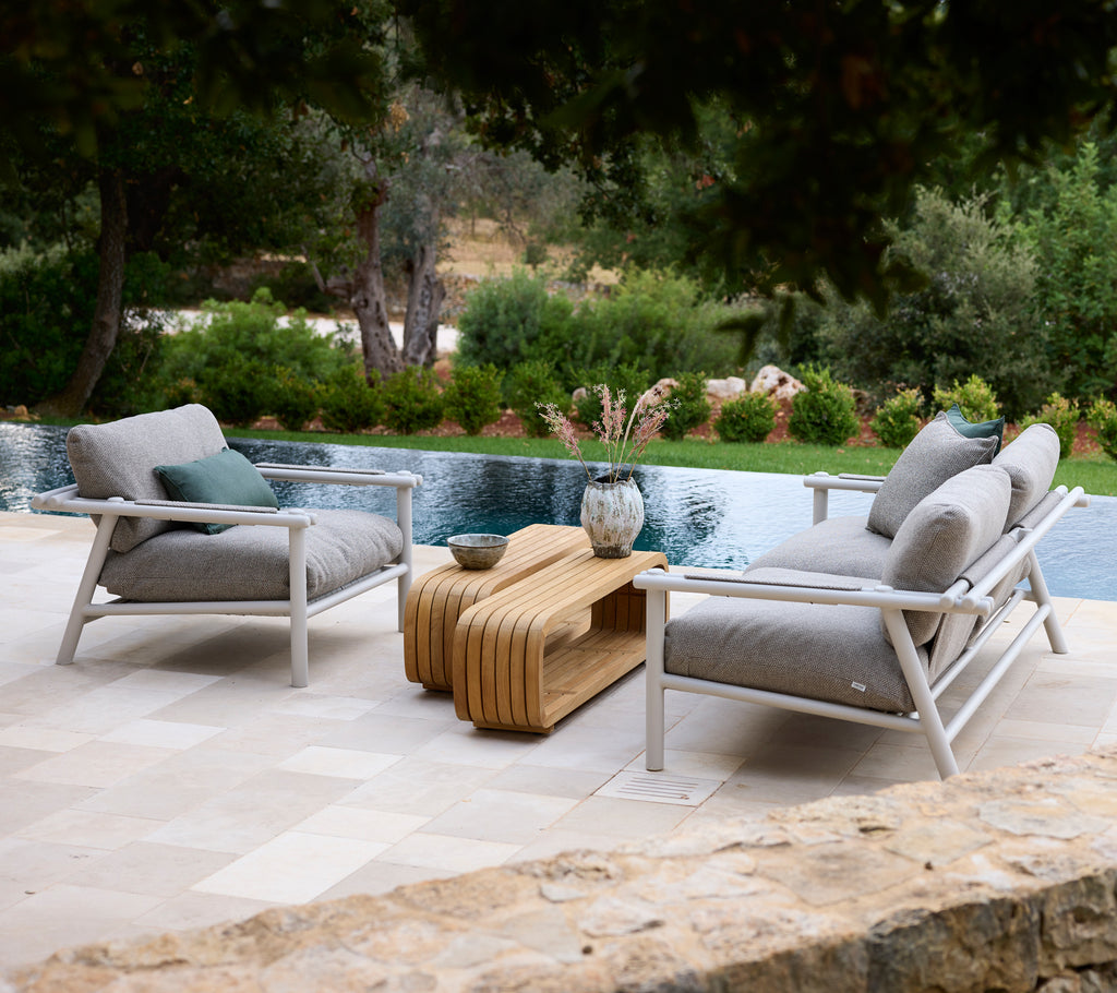 Modern lounge area featuring white chairs with grey cushions and a wooden coffee table.