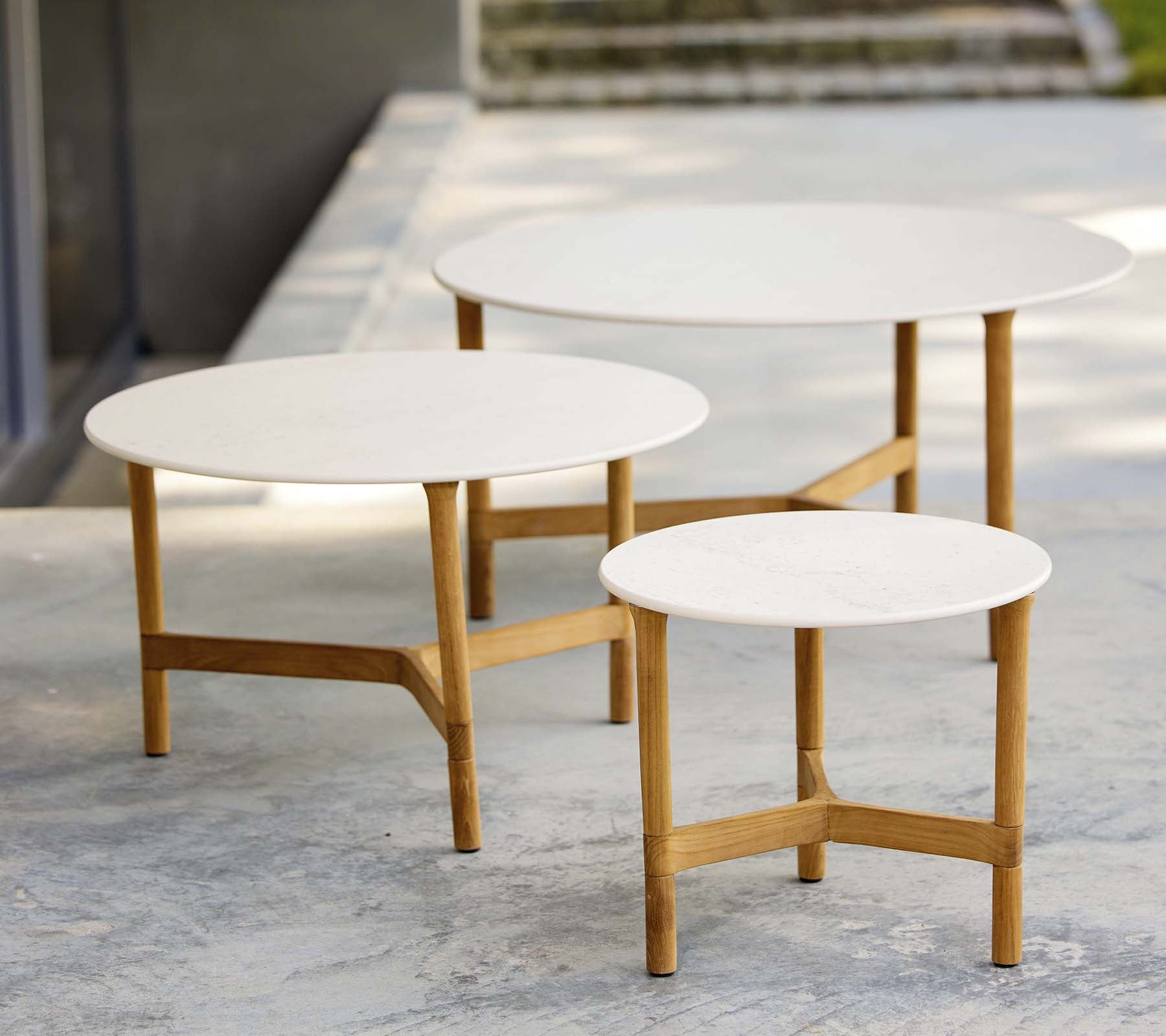 Three modern coffee tables in varying sizes with white tops and wooden legs, displaying a stylish and minimalist design.