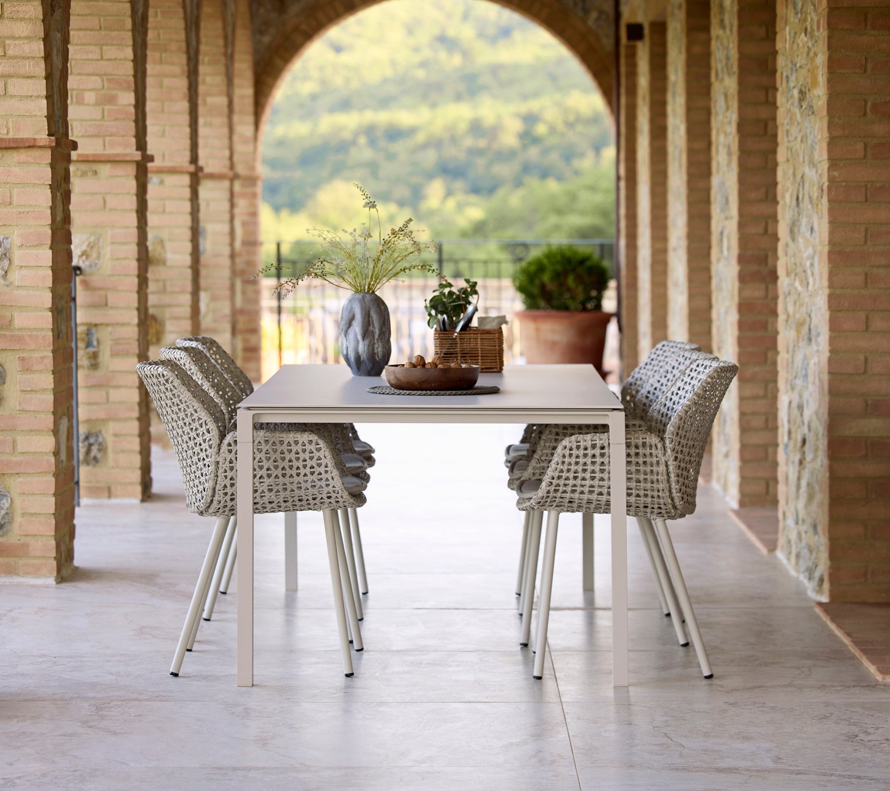 Elegant dining setup featuring a Pure sand dining table surrounded by Vibe dining chairs, accented by a vase and decorative elements.